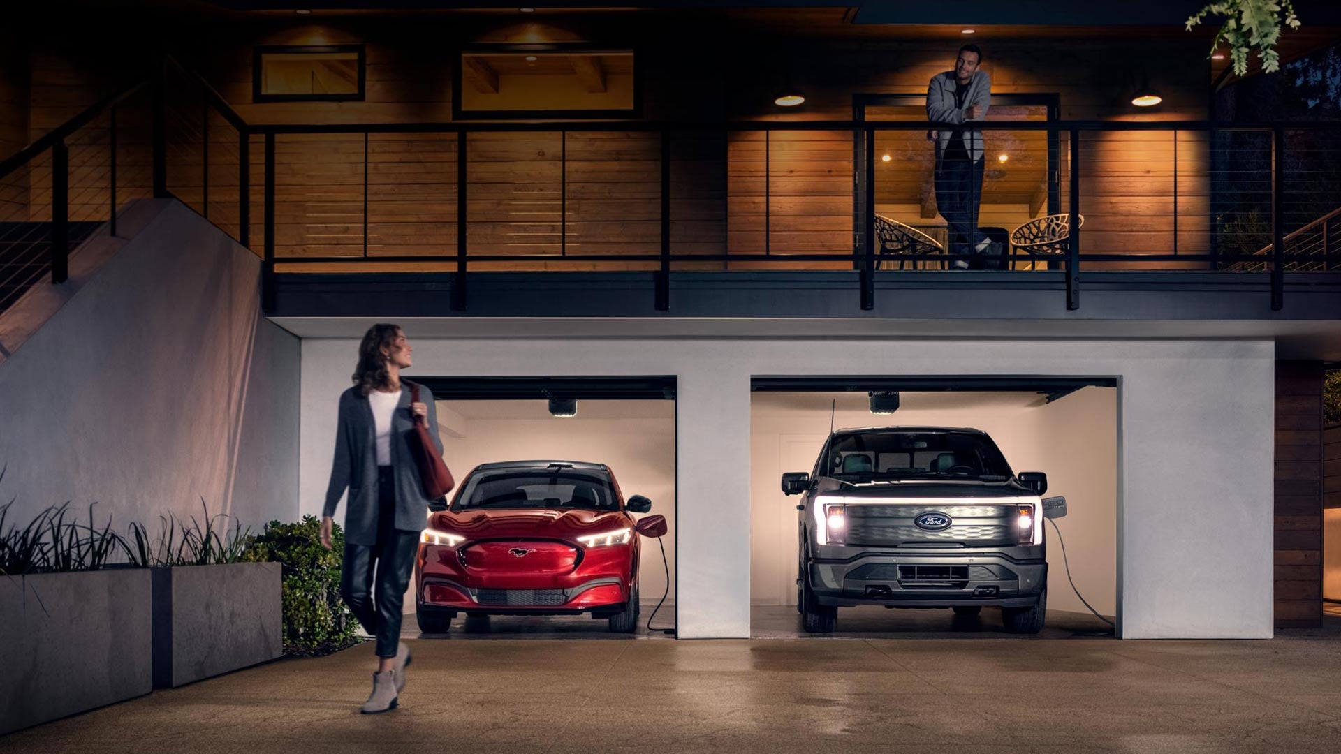 Woman walking out from home garage with a 2024 Mustang® Mach-E and Ford Lightning® truck in plugged-in and charging | Crain Ford of Little Rock in Little Rock AR