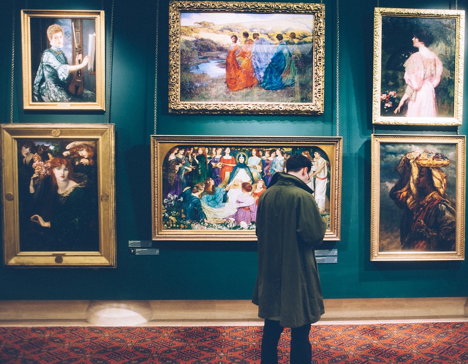 A man standing in front of a wall of art in a museum. | Museums around Little Rock, AR.