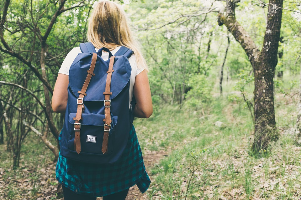 A woman carrying a backpack hiking in a wooded area. | Hiking trails near Little Rock, AR.