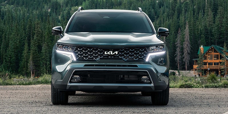 Front view of a dark turquoise 2022 Kia Sorento parked with the lights on in the woods. | Kia dealer on Little Rock, AR.