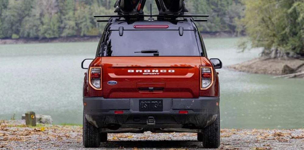 Rear view of a red 2022 Ford Bronco parked in front of a lake in a wooded area. | Ford dealer in Little Rock, AR.