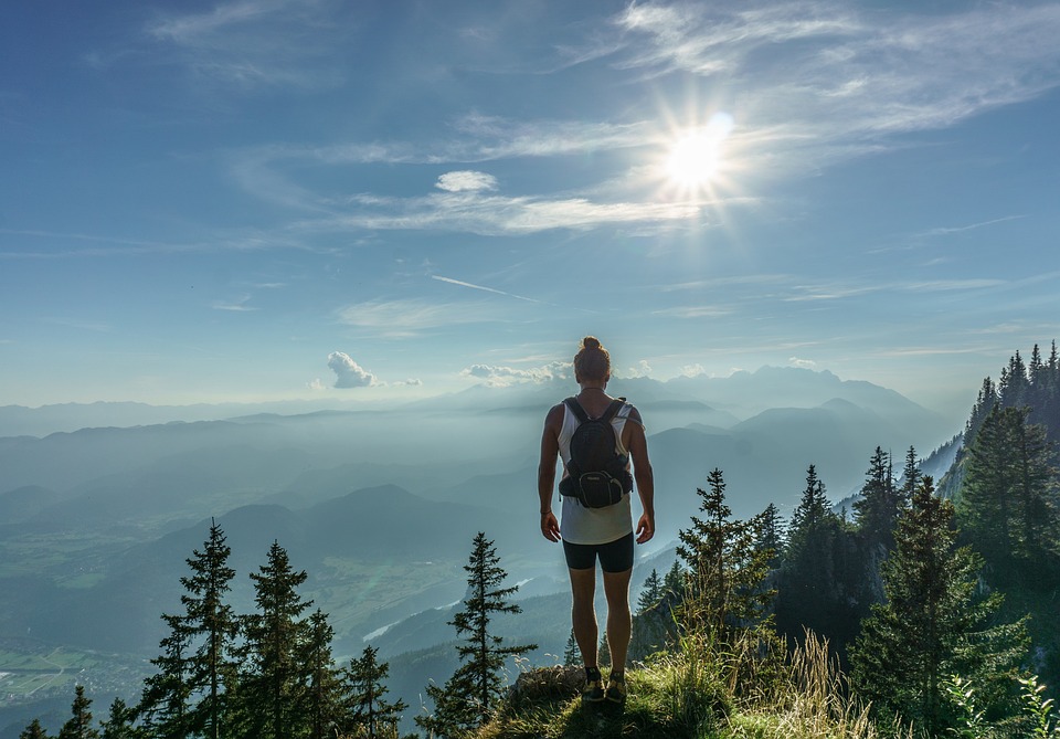 A hiker standing at the top of a mountain surrounded by trees and mountains up ahead. | Fun activities for Fall around Little Rock, AR.