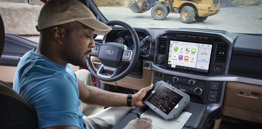 A man sitting in the driver seat of a 2023 Ford F-150 holding a tablet. | Ford service around Little Rock, AR.
